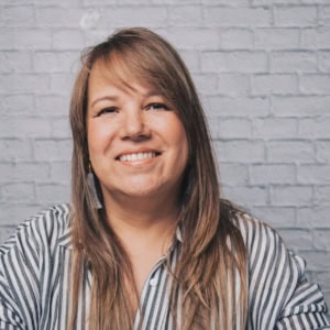 Frau mit braunen langen haaren lächelt in die Kamera