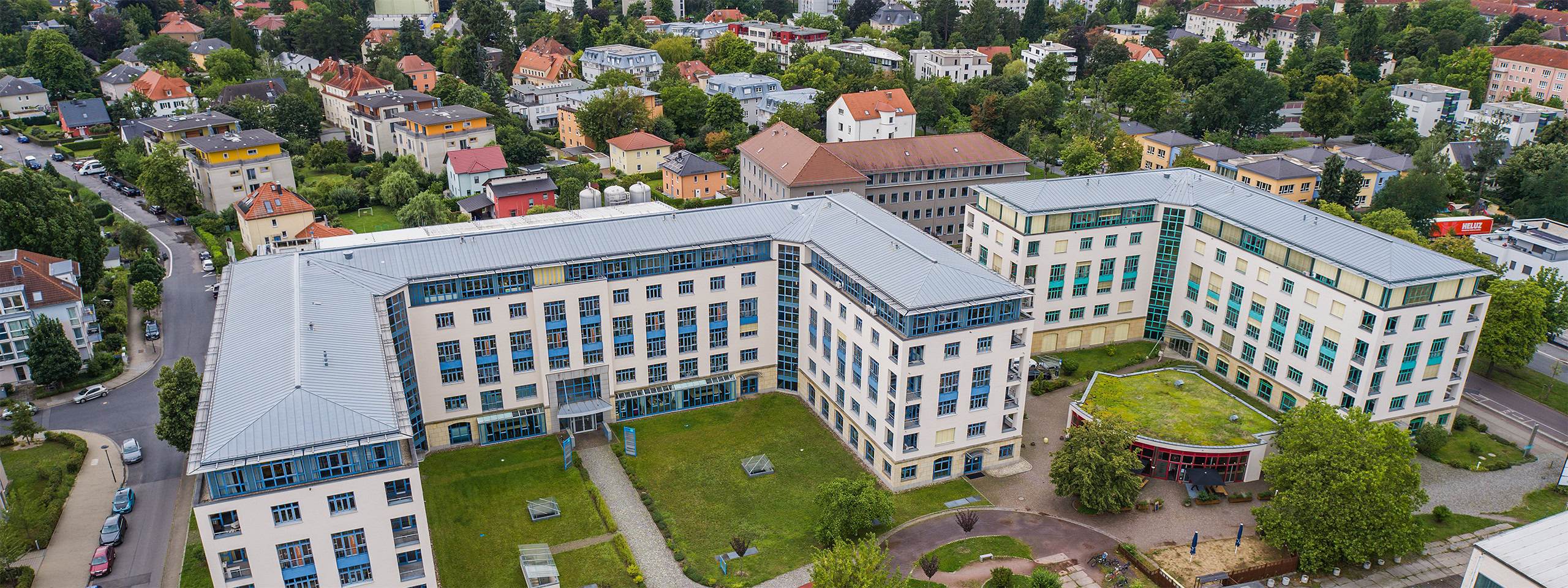Luftaufnahme der multicareer Akademie in einer urbanen Umgebung mit modernen Gebäuden und Grünflächen, Teil des Über Uns Abschnitts.