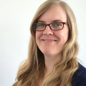Porträt einer Frau mit Brille, die für die multicareer Akademie arbeitet, im professionellen Umfeld.